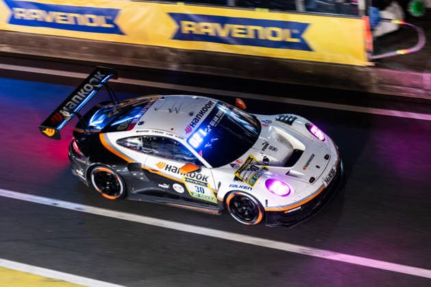 Der Porsche 911 GT3 R (992) Evo26 mit der Startnummer 30 vom Team Hankook Competition mit den Fahrern Jongkyum Kim, Roelof Bruins, Steven Cho und Marco Seefried fährt während des 24h Rennens bei Nacht in der Boxengasse auf der Grand-Prix-Strecke des Nürburgrings. Nürburg Rheinland-Pfalz Deutschland