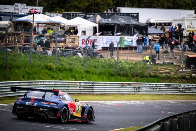 Der Mercedes-AMG GT3 von Mercedes-AMG Team Verstappen Racing durchfährt eine Kurve auf der Nordschleife am Nürburgring. Das Fahrzeug Daniel Juncadella & Jules Gounon & Lucas Auer & Max Verstappen (Mercedes-AMG Team Verstappen Racing) trägt die charakteristische Red-Bull-Lackierung in Dunkelblau mit dem markanten Red-Bull-Logo auf der Fahrzeugseite. Sponsoren wie H&R und Multimatic sind auf der Karosserie erkennbar. Im Hintergrund verfolgen zahlreiche Zuschauer das Renngeschehen von einer Anhöhe, ein ROWE-Banner ist an der Absperrung befestigt. Mercedes-AMG GT3 3 von Verstappen Racing auf der Nordschleife Copyright: xMichaelxGelhardtx