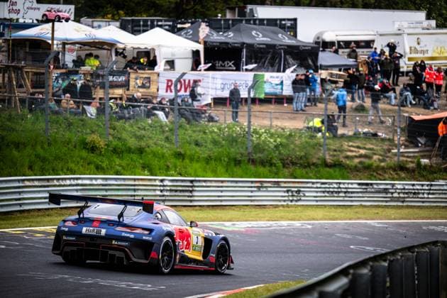 Der Daniel Juncadella & Jules Gounon & Lucas Auer & Max Verstappen (Mercedes-AMG Team Verstappen Racing) von Mercedes-AMG Team Verstappen Racing durchfährt eine Kurve auf der Nordschleife des Nürburgrings. Das in dunklem Blau gehaltene Fahrzeug mit markanter Red-Bull-Lackierung und der Startnummer 3 präsentiert sich mit Sponsoren wie H&R, Michelin und Sparco auf dem Asphalt. Im Hintergrund verfolgen zahlreiche Zuschauer das Renngeschehen von einem Schotterwall, während ein ROWE-Banner die Streckenbegrenzung ziert. Mercedes-AMG GT3 3 von Verstappen Racing in der Kurve am Nürburgring Copyright: xMichaelxGelhardtx