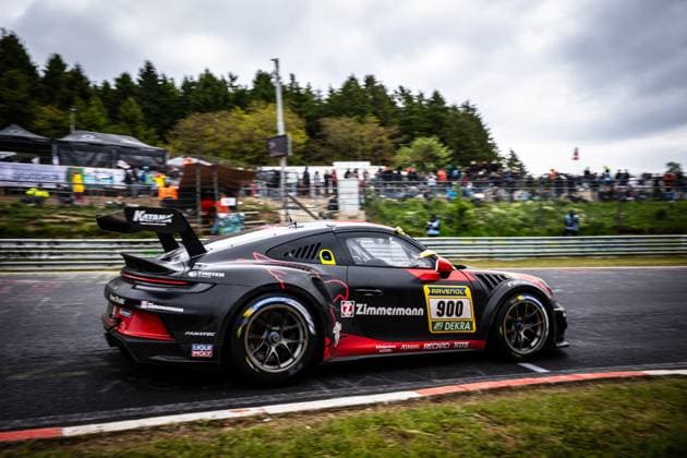 Der Porsche 911 GT3 von BLACK FALCON Team ZIMMERMANN (Alexander Hardt & Bear & Benjamin Hites & Benjamin Koslowski & Paul Meijer (BLACK FALCON Team ZIMMERMANN)) durchfährt eine Kurve auf dem Nürburgring beim ADAC RAVENOL 24h Nürburgring 2026. Das schwarz-rote Fahrzeug mit der Startnummer 900 trägt prominente Sponsoren wie Zimmermann, RAVENOL, Fanatec und LIQUI-MOLY auf der Karosserie. Im Hintergrund sind zahlreiche Zuschauer an der Streckenbegrenzung zu sehen. Porsche 911 GT3 900 von BLACK FALCON Team ZIMMERMANN auf dem Nürburgring Copyright: xMichaelxGelhardtx