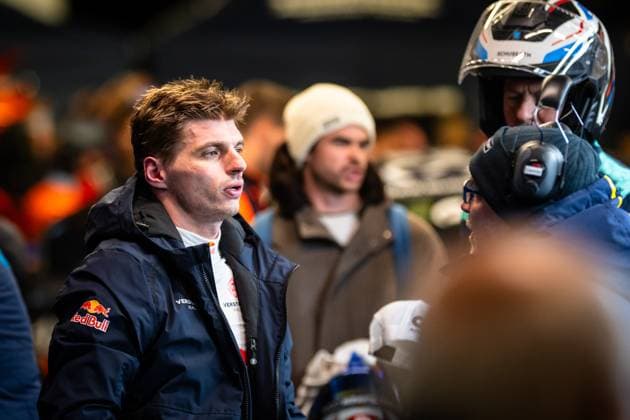 Max Verstappen von Mercedes-AMG Team Verstappen Racing steht im Fahrerlager des Nürburgrings und unterhält sich mit Teammitgliedern. Er trägt eine dunkle Teamjacke mit Red Bull- und Verstappen Racing-Logo. Im Hintergrund ist ein Fahrer mit einem Schuberth-Helm zu sehen. Max Verstappen im Fahrerlager beim 24h Nürburgring 2026 Copyright: xMichaelxGelhardtx