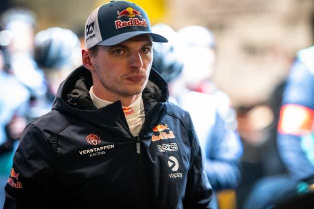 Max Verstappen ist im Fahrerlager des Nürburgrings zu sehen. Er trägt die dunkelblaue Teamjacke von Mercedes-AMG Team Verstappen Racing mit den Logos von Red Bull, Sparco und Viaplay. Auf seinem Cap ist ebenfalls das Red-Bull-Logo zu erkennen. Im Hintergrund sind unscharf weitere Personen in Teamkleidung zu sehen. Max Verstappen im Fahrerlager beim 24h Nürburgring 2026 Copyright: xMichaelxGelhardtx