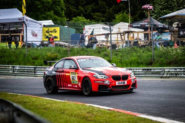 Der Aidan Mulready & Alvaro Fontes & Andreas Simon & James Breakell (Breakell Racing) von Breakell Racing nimmt einen Kurvenausgang auf der Nordschleife des Nürburgrings. Das rot-schwarz lackierte BMW M240i Racing Coupé mit der Startnummer 667 präsentiert sich mit Sponsoren wie RAVENOL, Falken, Goodyear und H&R. Im Hintergrund sind Zuschauerbereiche, Werbebanner sowie das charakteristische Grün der Eifellandschaft zu erkennen. BMW M240i Racing 667 von Breakell Racing auf der Nordschleife Copyright: xMichaelxGelhardtx
