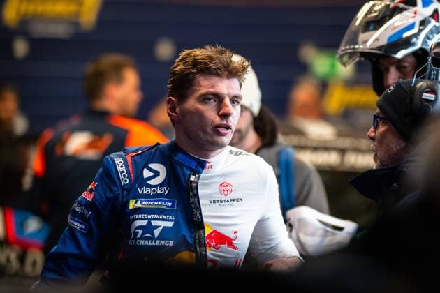 Max Verstappen ist im Fahrerlager des Nürburgrings im Gespräch zu sehen. Er trägt den blauen Rennoverall von Mercedes-AMG Team Verstappen Racing mit Sponsoren wie Viaplay, Michelin, Red Bull und Sparco sowie dem Intercontinental GT Challenge-Logo. Im Hintergrund sind weitere Personen und Teamfahrzeuge unscharf zu erkennen. Max Verstappen im Gespräch beim 24h Nürburgring 2026 Copyright: xMichaelxGelhardtx