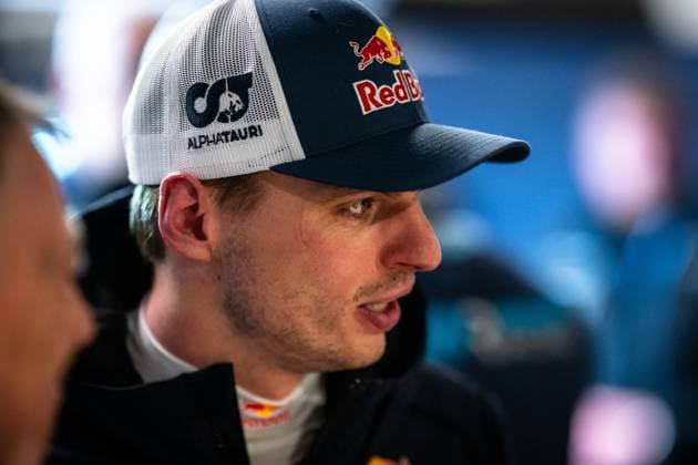 Max Verstappen ist im Fahrerlager des Nürburgrings zu sehen. Er trägt eine Kappe mit Red Bull- und AlphaTauri-Branding sowie einen dunklen Teamjacket mit Red-Bull-Logo. Im Hintergrund sind weitere Personen unscharf zu erkennen. Das Bild entstand im Rahmen des ADAC RAVENOL 24h Nürburgring 2026. Max Verstappen im Fahrerlager beim 24h Nürburgring 2026 Copyright: xMichaelxGelhardtx