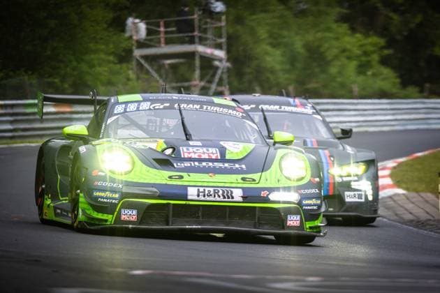 Der Porsche 911 GT3 R Daan Arrow & Dylan Pereira & Patrick Assenheimer & Tobias Müller (48 LOSCH Motorsport by BLACK FALCON) von 48 LOSCH Motorsport by BLACK FALCON durchfährt mit eingeschalteten Scheinwerfern eine Kurve auf der Nordschleife des Nürburgrings. Das charakteristisch grün-schwarz lackierte Fahrzeug trägt Sponsoren wie Liqui-Moly, H&R, Goodyear, Fanatec und CODEX. Im Hintergrund folgt ein weiterer Porsche 911 GT3 R dicht auf. Porsche 911 GT3 R 48 von LOSCH Motorsport by BLACK FALCON auf der Nordschleife Copyright: xMichaelxGelhardtx
