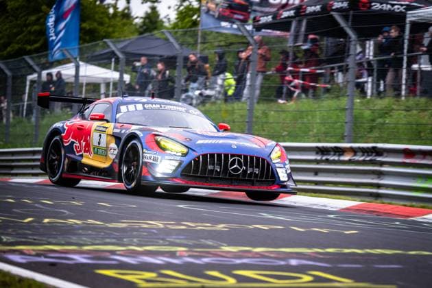 Der Mercedes-AMG GT3 von Mercedes-AMG Team Verstappen Racing mit der Startnummer Daniel Juncadella & Jules Gounon & Lucas Auer & Max Verstappen (Mercedes-AMG Team Verstappen Racing) nimmt eine Kurve auf der Nordschleife des Nürburgrings. Das Fahrzeug trägt das markante Red-Bull-Livery in Blau, Rot und Gelb mit Gran Turismo- und RAVENOL-Sponsoring. Die eingeschalteten Scheinwerfer und der aggressive Anpressdruck unterstreichen das hohe Tempo auf dem nassen Asphalt. Im Hintergrund verfolgen zahlreiche Zuschauer das Rennen hinter den Leitplanken. Mercedes-AMG GT3 3 von Verstappen Racing auf der Nordschleife Copyright: xMichaelxGelhardtx
