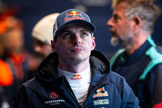 Porträt eines Rennfahrers in Red Bull Teamkleidung mit Cap und schwarzer Jacke im Fahrerlager des Nürburgring. Im Hintergrund sind weitere Personen und Teamzelte sichtbar. Max Verstappen im Red Bull Teamwear am Nürburgring Copyright: xMichaelxGelhardtx