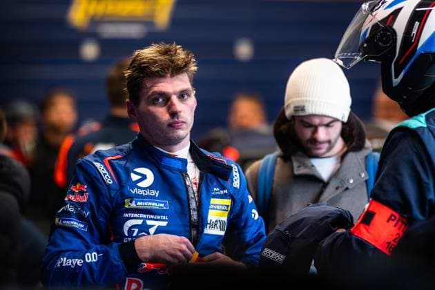 Ein Fahrer in blauem Rennanzug mit Red Bull- und Michelin-Sponsoring steht im Fahrerlager. Der Rennfahrer trägt die charakteristische Teamkleidung mit diversen Sponsorenlogos und wird von weiteren Personen im Paddock umgeben. Fahrer im Paddock bei der 24h Nürburgring 2026 Copyright: xMichaelxGelhardtx