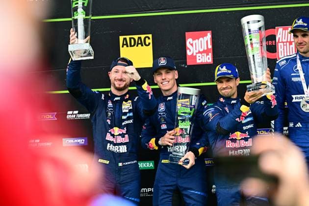 Luca Engstler und Mirko Bortolotti von Red Bull Team ABT präsentieren stolz ihre Trophäe auf dem Podium. Das Team in den klassischen dunkelblauen Rennanzügen mit Red Bull Sponsoring triumphiert beim 24h-Rennen auf der legendären Nordschleife. Red Bull Team ABT feiert Podium-Erfolg auf dem Nürburgring Copyright: xMichaelxGelhardtx