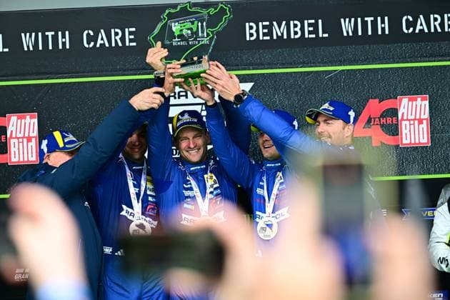 Die Mercedes-AMG GT3 von RAVENOL Motorsport mit Luca Stolz, Maro Engel und Maxime Martin triumphiert beim ADAC RAVENOL 24h Nürburgring 2026. Das Team hebt den grün-schwarzen Pokal der Siegerehrung auf dem Podium, während die Fahrer in ihren blauen Team-Overalls ihre Freude über den Langstrecken-Erfolg ausstrahlen. Mercedes-AMG 80 von RAVENOL Motorsport siegt beim 24h Nürburgring 2026 Copyright: xMichaelxGelhardtx