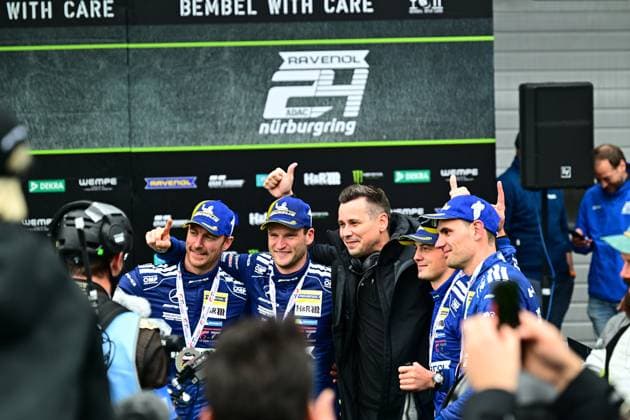 Die Fahrer von Mercedes-AMG Team RAVENOL präsentieren stolz ihre Trophäe nach dem Sieg beim 24h Nürburgring. Die Crew in blauer Teamkleidung mit RAVENOL- und H&R-Sponsoring zeigt Daumen hoch vor dem Podium mit Nürburgring-Branding. Mercedes-AMG Team RAVENOL 80 feiert Sieg bei 24h Nürburgring Copyright: xMichaelxGelhardtx