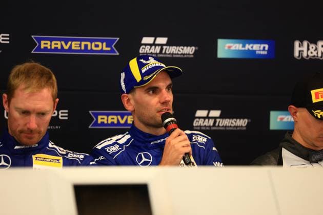 Luca Stolz und Maxime Martin von Mercedes-AMG Team RAVENOL präsentieren sich bei einer Pressekonferenz. Die Fahrer in den charakteristischen blauen Mercedes-AMG Overalls sitzen am Podium mit Mikrofonen vor Sponsorenwerbung. Mercedes-AMG Team RAVENOL 80 bei Pressekonferenz zum 24h Nürburgring