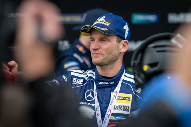 Maro Engel von Mercedes-AMG Team RAVENOL steht im Fahrerlager und trägt die blaue Teamkleidung mit Mercedes-AMG und RAVENOL-Sponsoring. Der Fahrer der Startnummer 80 ist in Gespräche vertieft. Maro Engel im Fahrerlager des 24h Nürburgring Copyright: xMichaelxGelhardtx