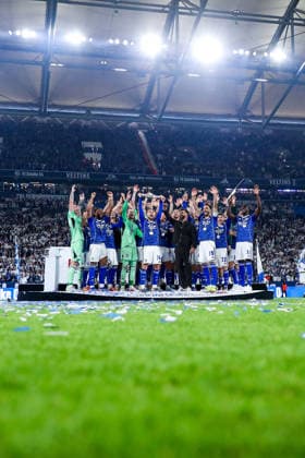 17.05.2026, Fußball, FC Schalke 04 - Eintracht Braunschweig, 34. Spieltag, 2. Fußball Bundesliga, Veltins-Arena Gelsenkirchen, Saison 2025 2026: Schalke 04 ist Meister der 2. Bundesliga. Die Mannschaft gewinnt die Meisterschaft und steht jubelnd auf dem Spielfeld. Freude und Emotionen nach dem Sieg. Adil Aouchiche (Schalke04 24) steht jubelnd mit der Meisterschale auf dem Podest neben Cheftrainer Miron Muslic (Schalke04) DFB regulations prohibit any use of photographs as image sequences and or quasi-video. Nordrhein-Westfalen Deutschland