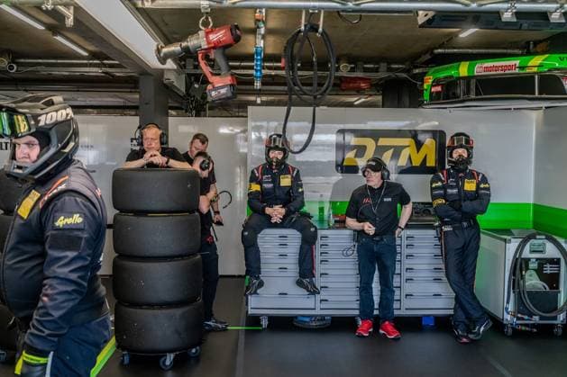 Boxenszene mit Mechanikern und Team-Personal in einer Renngarage. Reifen, Werkzeuge und Ausrüstung sind sichtbar, mehrere Personen in schwarzer Teamkleidung und Helmen bereiten sich auf einen Rennablauf vor. DTM Team in der Garage am Circuit Park Zandvoort Copyright: xMichaelxSchäferx