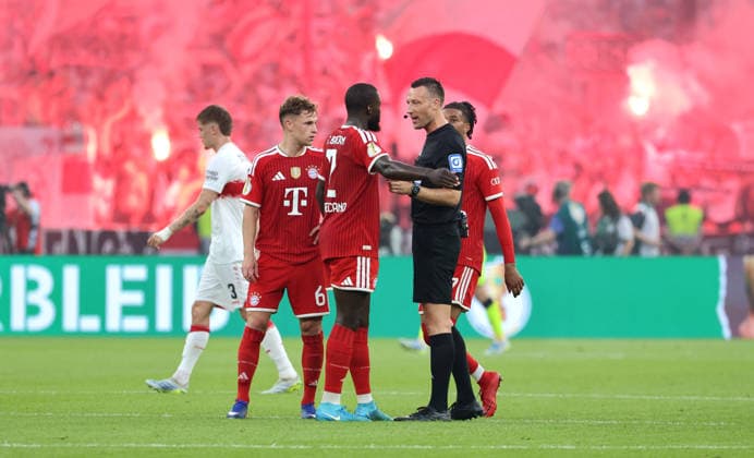Dayot Upamecano redet mit Schiedsrichter Sven Jablonski, dahinter Pyrotechnik, Bengalos, Feuerwerk im Stuttgarter Fanblock Fußball Fussball Finale DFB Pokal 2026 Saison 2025 2026 23.05.2026 FC Bayern München FCB vs VfB Stuttgart