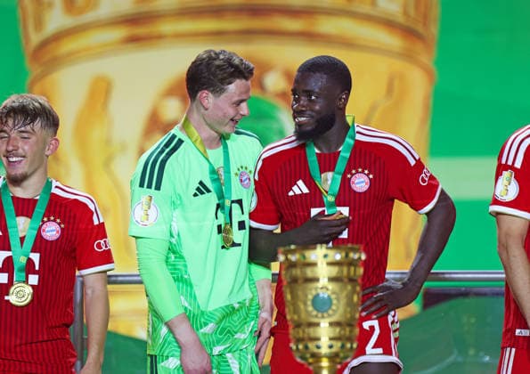 Fussball, Herren, DFB-Pokal Finale, Saison 2025 2026, FC Bayern München - VFB Stuttgart, Olympiastadion Berlin Die Mannschaft des FC Bayern München feiert den Gewinn des DFB-Pokal hier nach dem Spiel, im Bild Jonas Urbig (FC Bayern München) (li.) mit Dayot Upamecano (FC Bayern München) (re.) im Gespräch DFB, DFL regulations prohibit any use of photographs as image sequences and or quasi-video