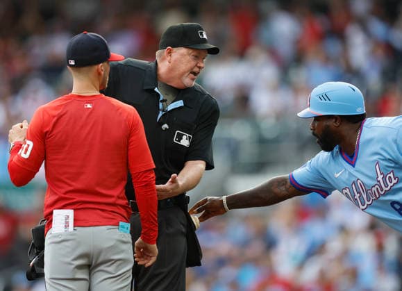Third base coach Tommy Watkins 84 of the Atlanta Braves tries to grab a baseball from the pocket of home plate umpire Ron Kulpa while Kulpa is arguing with Washington Nationals manager Blake Butera 10 during the game at Truist Park on Saturday, May 23, 2026 in Atlanta, Georgia.  ATL20260523133 MikexZarrilli