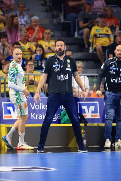 SC Magdeburg-Trainer Bennet Wiegert steht konzentriert an der Seitenlinie der SAP Arena und gibt mit Handgesten taktische Anweisungen. Links im Bild ist Rechtsaußen Daniel Pettersson ( 11, SC Magdeburg) im weißen Auswärtstrikot zu sehen. Bennet Wiegert (SC Magdeburg) gibt Anweisungen neben Daniel Pettersson in der SAP Arena