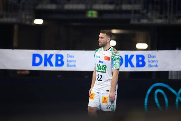 Lukas Mertens ( 36, Linksaußen, SC Magdeburg) steht im weißen Auswärtstrikot mit der Rückennummer 22 auf dem Spielfeld der SAP Arena. Im Hintergrund ist die DKB-Bandenwerbung deutlich sichtbar. Lukas Mertens ( 36, SC Magdeburg) in der SAP Arena