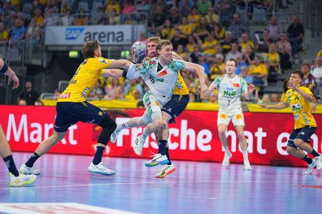 Ein Spieler des SC Magdeburg ( 10, weißes Trikot) kämpft sich unter starkem Druck zweier Rhein Neckar Löwen-Verteidiger durch und zieht zum Wurf ab. Gino Steenaerts ( 14, Rhein Neckar Löwen) ist rechts im Bild zu sehen. SC Magdeburg 10 durchbricht Löwen-Deckung in der SAP Arena