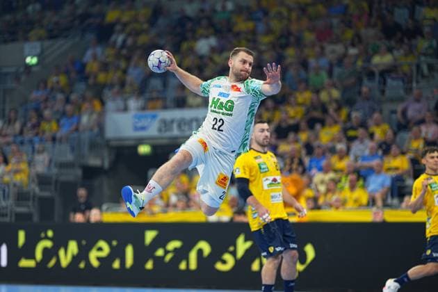 Magnus Saugstrup ( 23; SC Magdeburg) springt mit dem Ball in der Hand zum Wurf ab, während Jannik Kohlbacher ( 80; Rhein Neckar Löwen) im Hintergrund zu sehen ist. Die vollbesetzte SAP Arena bildet die Kulisse des DAIKIN HBL-Duells. Magnus Saugstrup ( 23; SC Magdeburg) beim Sprungwurf in der SAP Arena