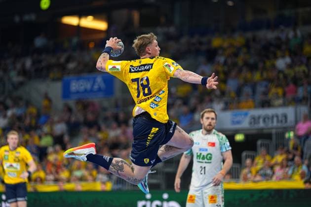 Edwin Aspenbäck ( 78; Rhein Neckar Löwen) springt in gelb-blauem Trikot ab und holt mit dem Ball zum Wurf aus. Im Hintergrund ist Albin Lagergren ( 21; SC Magdeburg) im weißen Trikot zu sehen. Edwin Aspenbäck ( 78; Rhein Neckar Löwen) beim Sprungwurf in der SAP Arena