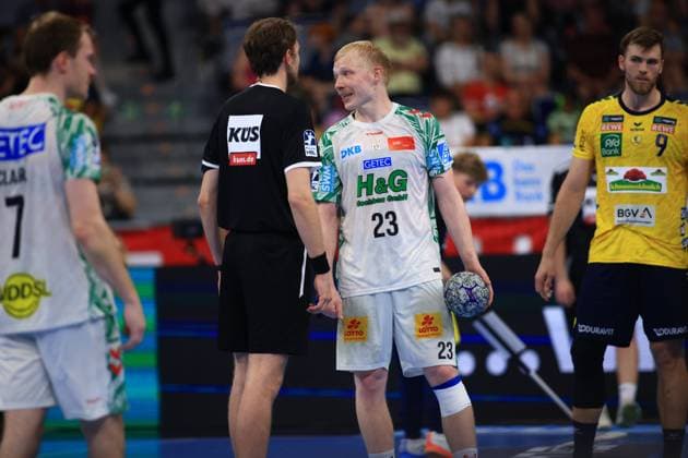 Magnus Saugstrup ( 23; SC Magdeburg) steht mit dem Ball in der Hand und spricht mit einem Schiedsrichter in der SAP Arena. Im Hintergrund sind Felix Claar ( 7; SC Magdeburg) sowie Steven Plucnar Jacobsen ( 9; Rhein Neckar Löwen) zu sehen. Magnus Saugstrup ( 23; SC Magdeburg) im Gespräch mit Schiedsrichter