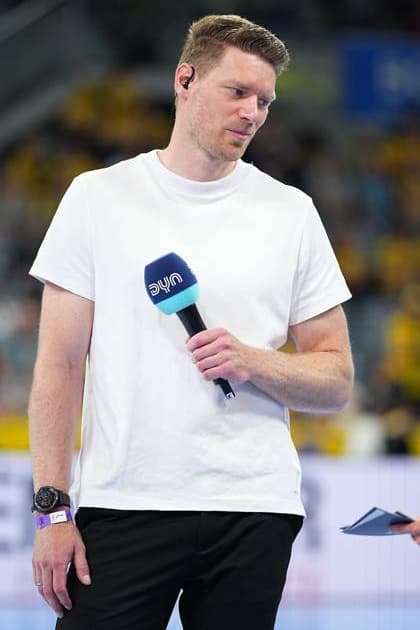 Tobias Reichmann steht mit einem DYN-Mikrofon in der Hand auf dem Spielfeld der SAP Arena. Er trägt ein weißes T-Shirt und ein In-Ear-Headset. Tobias Reichmann als DYN-Moderator in der SAP Arena