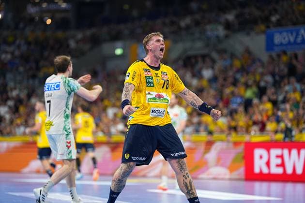 Edwin Aspenbäck ( 78; Rhein Neckar Löwen) reißt die Fäuste hoch und jubelt lautstark im gelben Trikot in der SAP Arena. Im Hintergrund ist Felix Claar ( 7; SC Magdeburg) im weißen Trikot zu sehen. Edwin Aspenbäck ( 78; Rhein Neckar Löwen) jubelt in der SAP Arena