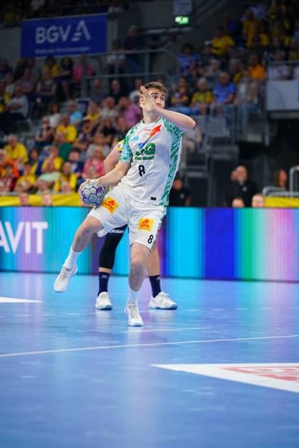 Manuel Zehnder ( 8, SC Magdeburg) springt mit dem Ball in der Hand zum Wurf ab, das weiße Trikot klar erkennbar. Im Hintergrund ist ein Gegenspieler in dunklem Trikot zu sehen, die Tribünen der SAP Arena sind mit Zuschauern gefüllt. Manuel Zehnder ( 8; SC Magdeburg) beim Wurfansatz in der SAP Arena
