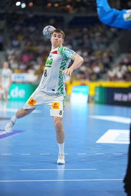 Manuel Zehnder ( 8; SC Magdeburg) springt in der SAP Arena hoch und bereitet einen Wurf vor, der Ball befindet sich auf Höhe seines Gesichts. Im Hintergrund sind die gefüllten Zuschauerränge der SAP Arena zu sehen. Manuel Zehnder ( 8; SC Magdeburg) beim Wurfansatz in der SAP Arena
