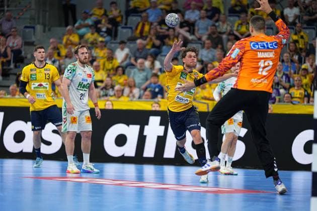 David Möré ( 15; Rhein Neckar Löwen) springt in der SAP Arena ab und wirft den Ball in Richtung SC-Magdeburg-Torwart Matej Mandi? ( 12). Im Hintergrund beobachten Sebastian Heymann ( 13; Rhein Neckar Löwen) und Albin Lagergren ( 21; SC Magdeburg) die Szene. David Möré ( 15; Rhein Neckar Löwen) beim Wurf gegen Matej Mandi?
