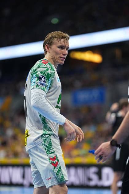 Gisli Thorgeir Kristjansson ( 10; SC Magdeburg) steht im weißen Magdeburg-Trikot auf dem Spielfeld der SAP Arena und blickt zur Seite. Im Hintergrund sind die gelb gekleideten Fans der Rhein-Neckar Löwen zu sehen. Gisli Thorgeir Kristjansson ( 10; SC Magdeburg) in der SAP Arena