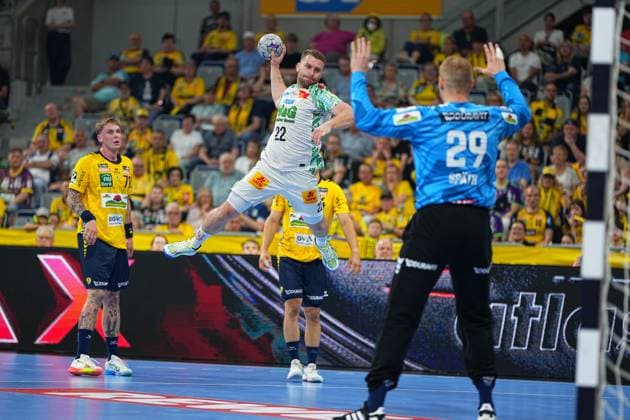 SC Magdeburg-Spieler Albin Lagergren ( 21) springt mit dem Ball in der Wurfphase und zielt auf das Tor, das von Rhein-Neckar-Löwen-Torhüter David Späth ( 29) gehalten wird. Im Hintergrund beobachtet Edwin Aspenbäck ( 78) die Szene vor der gelb gekleideten Heimfankurve in der SAP Arena. Albin Lagergren ( 21; SC Magdeburg) beim Sprungwurf gegen David Späth ( 29; Rhein Neckar Löwen)