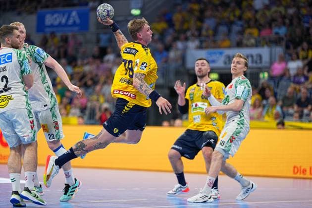 Edwin Aspenbäck ( 78, Rhein Neckar Löwen) zieht in gelbem Trikot zum Sprungwurf hoch und hält den Ball mit der rechten Hand über dem Kopf. Im Hintergrund ist Jannik Kohlbacher ( 80, Rhein Neckar Löwen) zu sehen, während zwei SC-Magdeburg-Spieler in weißen Trikots ( 22, 23) und ein weiterer ( 10) die Szene verfolgen. Edwin Aspenbäck ( 78; Rhein Neckar Löwen) beim Sprungwurf in der SAP Arena