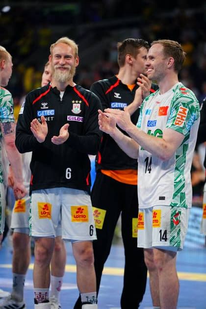 Matthias Musche ( 6) in schwarzer Trainingsjacke und Omar Ingi Magnusson ( 14) im weißen Spieltrikot des SC Magdeburg klatschen lächelnd in der SAP Arena. Beide stehen auf dem Spielfeld und wirken entspannt. Matthias Musche ( 6; SC Magdeburg) und Omar Ingi Magnusson ( 14; SC Magdeburg) applaudieren