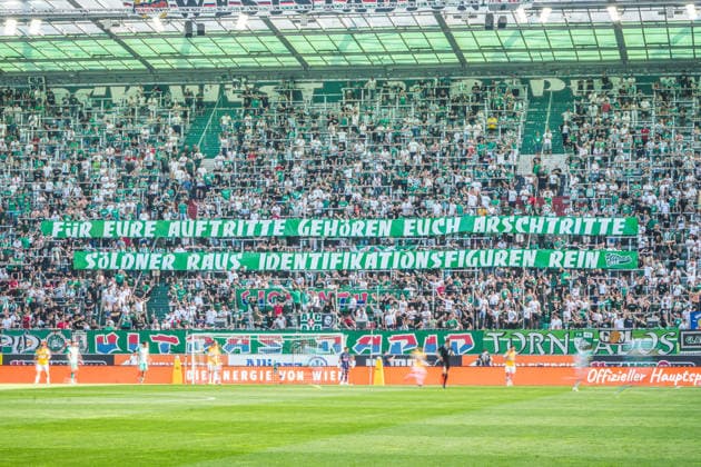 Fussball Österreich, Admiral Bundesliga Europacup-Playoff Finale ECL 2025 2026, SK Rapid Wien vs. SV Oberbank Ried - Allianz Stadion (Weststadion, Wien Hütteldorf): Banner der Ultras Rapid mit dem Schriftzug Für eure Auftritte gehören euch Arschtritte. Söldner raus, Identifikationsfiguren rein Copyright: xLukasxBierederx