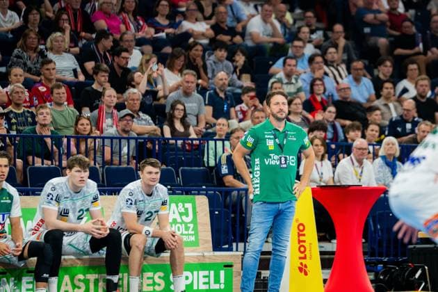 Ben Matschke, Trainer von Frisch Auf Göppingen, steht an der Seitenlinie in grünem Polo-Shirt. Sascha Brodbeck ( 21) und Oskar Sunnefeldt ( 27) sitzen auf der Bank in weißen Trikots des Vereins. Ben Matschke und Spieler von Frisch Auf Göppingen in der Barclays Arena Copyright: xPhilippHeistx