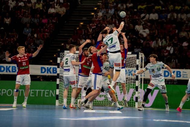 Frederik Bo Andersen springt zum Wurf ab und wirft den Ball in Richtung Tor, während Spieler von Frisch Auf Göppingen die Abwehr bilden. Die Szene zeigt einen intensiven Angriff des HSV Hamburg in der Barclays Arena mit Zuschauern im Hintergrund. Handball Verein Hamburg vs. Frisch Auf Göppingen Copyright: xPhilippHeistx