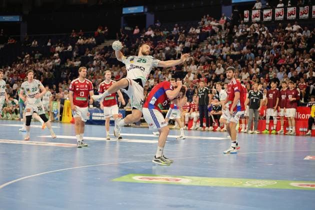 Ludvig Jurmala Åström springt zum Wurf ab und hält den Ball über dem Kopf, während Jacob Lassen ( 9; HSV Hamburg) in Abwehrposition darunter steht. Die Partie findet in der Barclays Arena vor vollbesetzten Rängen statt. Ludvig Jurmala Åström ( 25; Frisch Auf Göppingen) bei Sprungwurf gegen HSV Hamburg