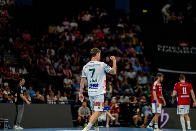 Victor Klöve trägt das weiße Trikot von Frisch Auf Göppingen und zeigt eine Jubelgeste während des Spiels gegen HSV Hamburg. Im Hintergrund sind HSV-Spieler in roten Trikots und Zuschauer in der Barclays Arena zu sehen. Handball Verein Hamburg vs. Frisch Auf Göppingen Copyright: xPhilippHeistx