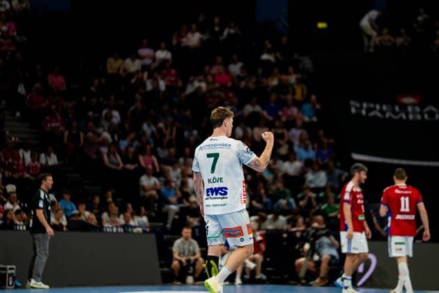 Victor Klöve trägt das weiße Trikot von Frisch Auf Göppingen mit der Nummer 7 und jubelt nach einem erfolgreichen Torwurf in der Barclays Arena. Im Hintergrund sind Spieler des HSV Hamburg in roten Trikots und Zuschauer der Arena zu sehen. Handball Verein Hamburg vs. Frisch Auf Göppingen Copyright: xPhilippHeistx