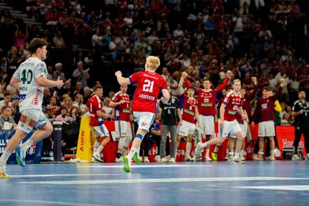 Frederik Bo Andersen ( 21; HSV Hamburg) läuft mit geballter Faust jubelnd über das Spielfeld der Barclays Arena, während seine Mannschaft im roten Trikot hinter ihm jubelt. Links sichtbar ist ein Spieler von Frisch Auf Göppingen ( 40) in weißem Trikot. Handball Verein Hamburg vs. Frisch Auf Göppingen Copyright: xPhilippHeistx