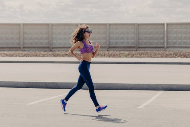 Eine durchtrainierte junge Frau in Sportkleidung, die im Freien auf einer offenen Straße läuft, wobei ihr Haar im Wind weht; sie trägt eine Sonnenbrille und blaue Leggings (Seitenansicht). Eine durchtrainierte junge Frau in Sportkleidung, die im Freien auf einer offenen Straße läuft, wobei ihr Haar im Wind weht; sie trägt eine Sonnenbrille und blaue Leggings (Seitenansicht). (License=RF) 25096371 ,model released, Symbolfoto Copyright: xZoonar.com ViorelxKurnosovx 25096371 ,model released, Symbolfoto ,property released