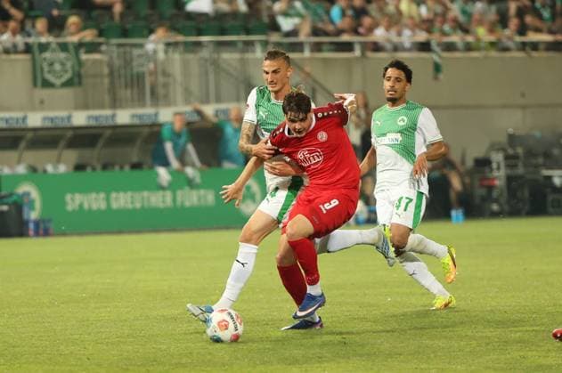 Philipp Ziereis ( 4; SpVgg Greuther Fürth) kämpft gegen einen Spieler von Rot-Weiss Essen ( 9) um den Ball, während Sayfallah Ltaief ( 47; SpVgg Greuther Fürth) den Zweikampf beobachtet. Die Szene findet im Sportpark Ronhof vor heimischer Kulisse statt. Philipp Ziereis ( 4; SpVgg Greuther Fürth) im Zweikampf gegen Rot-Weiss Essen