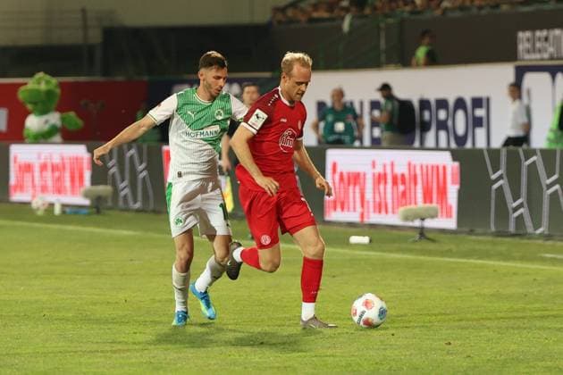 Ein Spieler von Rot-Weiss Essen setzt sich im Zweikampf gegen einen Spieler von SpVgg Greuther Fürth durch und kontrolliert den Ball. Die Szene findet im Stadion von Greuther Fürth vor gefüllten Rängen statt. Zweikampf zwischen Rot-Weiss Essen und SpVgg Greuther Fürth