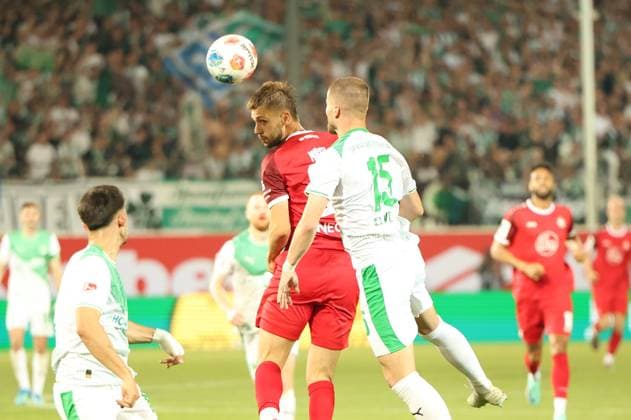 Ein Spieler von Rot-Weiss Essen gewinnt ein Kopfballduell gegen Jan Elvedi ( 15; SpVgg Greuther Fürth) im vollbesetzten Stadion. Der Ball ist dabei klar zu sehen, beide Spieler springen hoch. Kopfballduell zwischen Rot-Weiss Essen und Jan Elvedi ( 15; SpVgg Greuther Fürth)