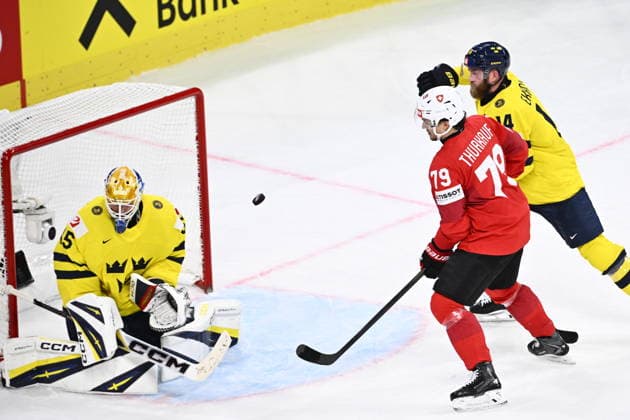 ZÜRICH, SCHWEIZ 20260528 Schweiz Calvin Thürkauf med Sveriges Mattias Ekholm bakom mot Sveriges malvakt Magnus Hellberg under torsdagens kvartsfinal i ishockey-VM mellan Schweiz och Sverige pa Swiss Life Arena i Zürich, Schweiz.